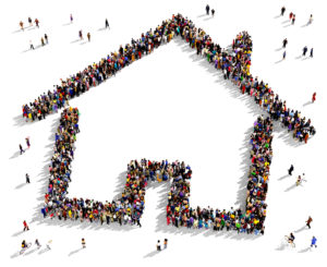 Large group of people seen from above gathered together in the shape of a house symbol